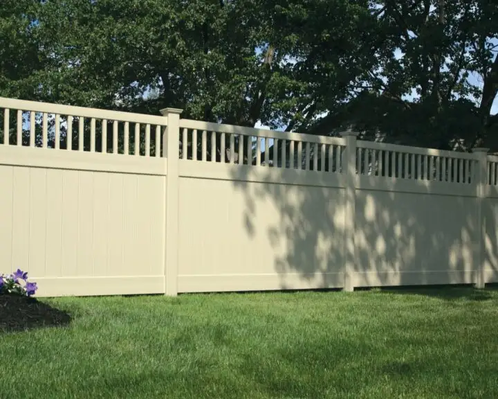 Light-colored privacy fence with framed spindles above the solid infill