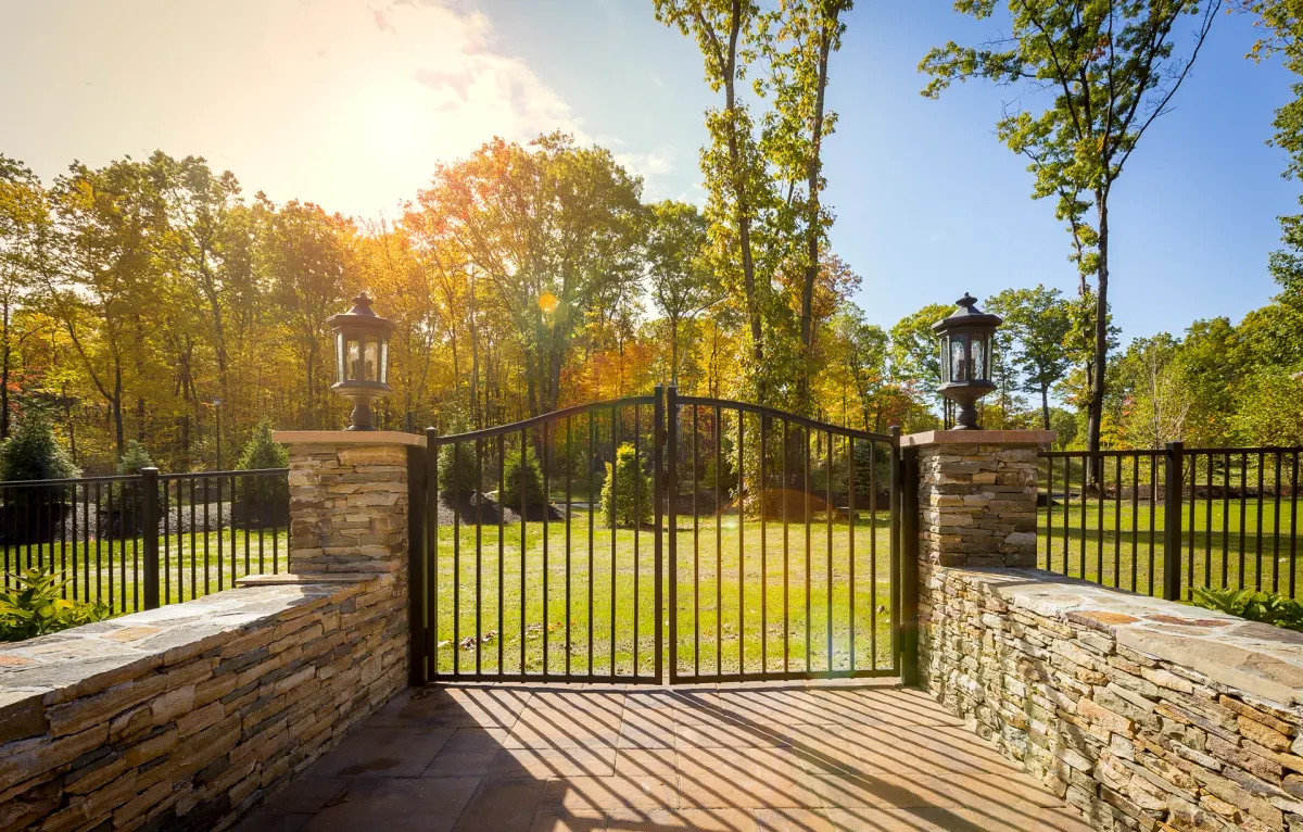 Black aluminum arched driveway gate with matching fence